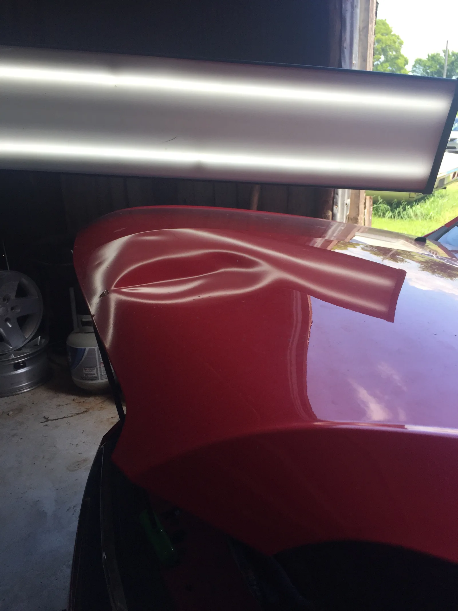Before PDR repair — large crease on red vehicle hood corner