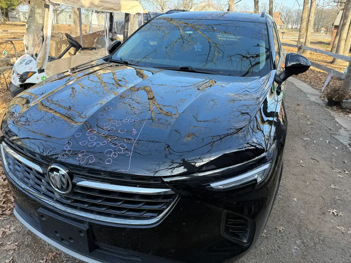 Black Buick SUV hood with every hail dent circled in chalk marker and the damaged zone outlined